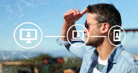 Image of connections with icons over caucasian man using smartphone. Connections, networks, data processing and technology concept digitally generated image.の写真素材