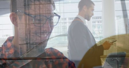 Image of caucasian businessman walking over businessman using smartphone. Global business and digital interface concept digitally generated image.の写真素材