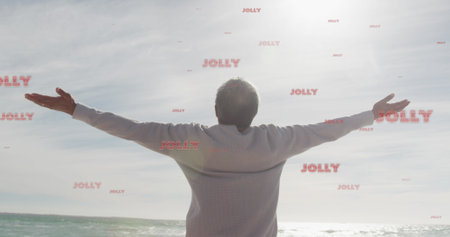 Image of jolly text over senior biracial man at beach. Christmas, celebration and digital interface...