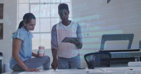 Image of data processing over two diverse women discussing over a plan at office. Business data...