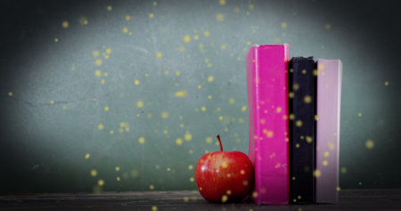 Image of glowing spots over apple and books on green background. international literacy day and reading concept digitally generated image.の写真素材