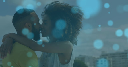 Image of light spots over african american couple embracing and kissing at beach. Global lifestyle, holidays and digital interface concept digitally generated image.の写真素材