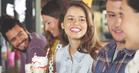 Group of diverse friends enjoying time together, holding drinks. Biracial male with curly hair,...