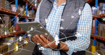 Image of network with icons over caucasian man using tablet in warehouse. Global business,...