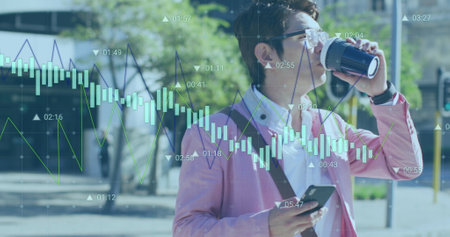 Image of graphs, changing numbers, asian man walking and drinking coffee while using cellphone....