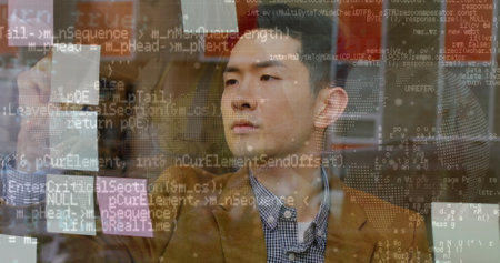 Asian male, looking at computer screen, wearing brown jacket. He has short black hair, focused eyes,...