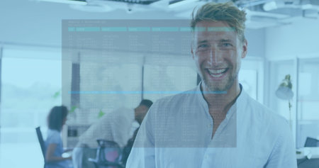 A Caucasian man is standing in office, smiling at camera. He has short, light brown hair, blue eyes, and is wearing casual light blue shirtの写真素材