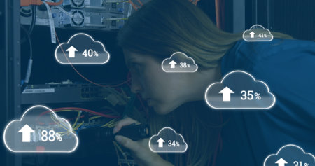 Image of clouds icons over caucasian female worker inspecting server room. global technology and digital interface concept digitally generated image.の写真素材