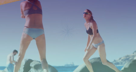 Image of glowing lights over group of diverse female friends playing beach volleyball. Friendship, summer and holiday concept digitally generated image.の写真素材