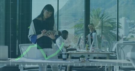 A woman of biracial is working on a tablet computer in a modern office. Global business finance connections and technology concept digitally generated image.の写真素材