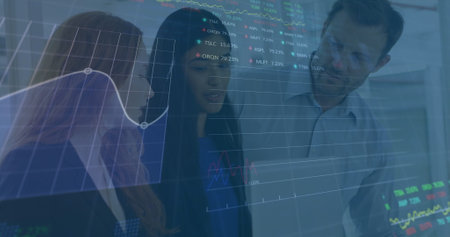 Image of graphs and trading board over diverse coworkers discussing reports on laptop in office. Digital composite, multiple exposure, business, stock market, teamwork, communication, technology.の写真素材