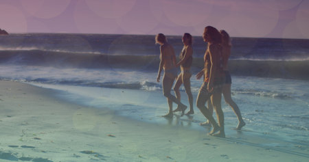 Image of glowing lights over group of diverse female friends by the sea. Friendship, summer and holiday concept digitally generated image.の写真素材