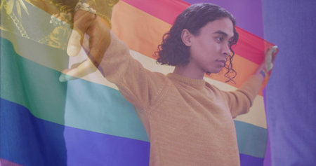 Image of diverse gay male couple holding hands over biracial gay man holding rainbow flag. Couple, love, pride, lgbtq, celebration and lifestyle, digitally generated image.の写真素材