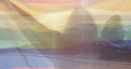 Image of sunset coast over happy diverse gay male couple holding rainbow flag. Couple, love, pride, lgbtq, celebration and lifestyle, digitally generated image.の写真素材