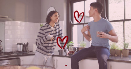 Image of red hearts over happy diverse gay male couple talking and laughing in kitchen. Couple,...