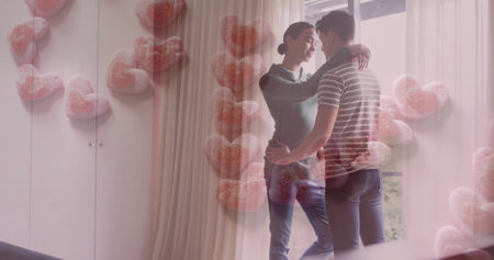 Image of love text in pink hearts over happy diverse gay male couple embracing at home. Couple, love, domestic life, lgbtq and lifestyle, digitally generated image.の写真素材