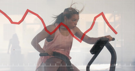 Exercising on stationary bike, woman with stock market graph image over. Fitness, exercise, cycling,...