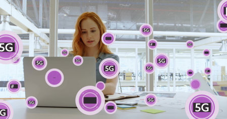 Image of circles with 5g over caucasian businesswoman using laptop in office. Global business, office, computing and digital interface concept digitally generated image.の写真素材