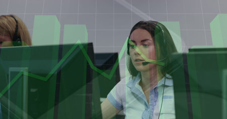 Image of multiple graphs over beautiful caucasian woman talking over headphones at office. Digital...