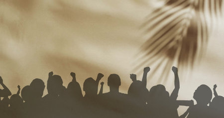 Image of silhouettes of people jumping and floating cloth over palm tree. Abstraction and lifestyle, digitally generated image.の写真素材