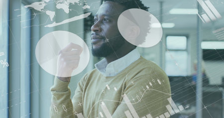African American male colleague looking at digital graphs. He has short black hair, wearing yellow sweaterの写真素材