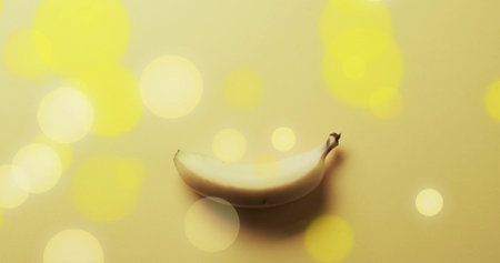 Composition of spots of light over banana on yellow background. Fruit, vegetarian food and organic healthy produce concept.の写真素材
