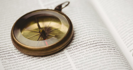 Image of close up of vintage golden compass on an open Christian Holy Bible book in the background....