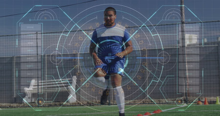 A biracial athlete wearing blue and white kit is training on a soccer field. He has short black hair, a beard, and is wearing soccer bootsの写真素材