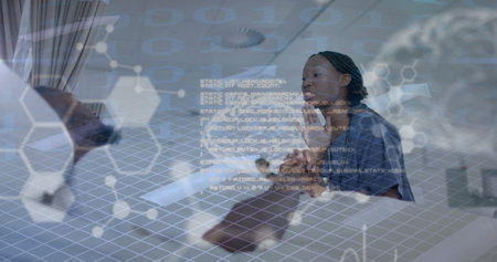 Image of human brain and data over african american female doctor and patient. Global medicine, healthcare, connections, computing and data processing concept digitally generated image.の写真素材