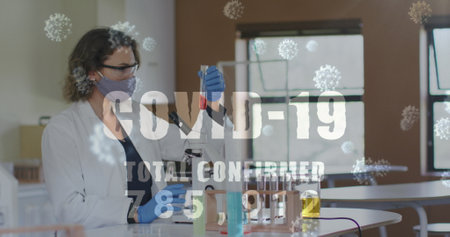 Image of word covid 19 total confirmed rising and cells with masked woman in lab. healthcare,...