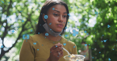 Image of network of connections with icons over african american woman eating salad. Global...