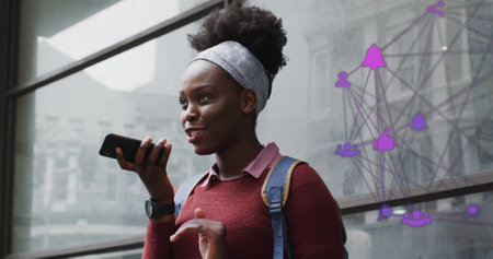 Image of network of connections with icons over african american woman talking on smartphone. Global...