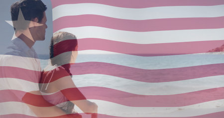 Couple embracing on beach over image of waving liberia flag. patriotism, love, relationship, celebration, independence, seasideの写真素材
