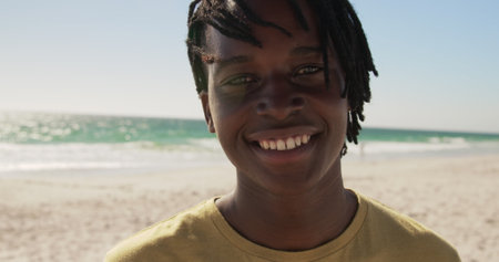 Front view of African American man standing on the beach. He is smiling and looking at camera 4kの写真素材
