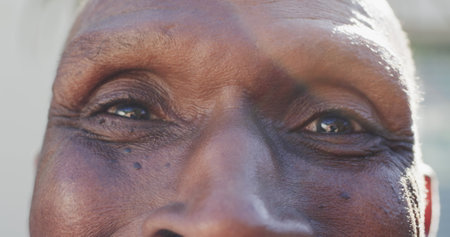 Portrait of close up of eyes of happy unaltered senior african american man, in slow motion. Retirement, happiness and senior lifestyle.の写真素材