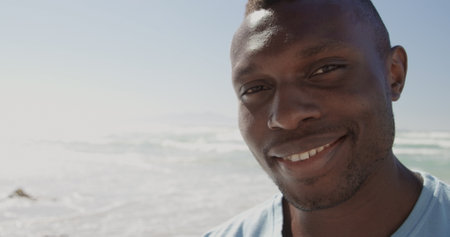 Front view of African american male volunteer looking at camera on the beachの写真素材