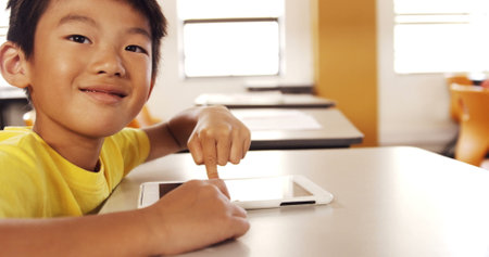 Boy using digital tablet in classroom at schoolの写真素材