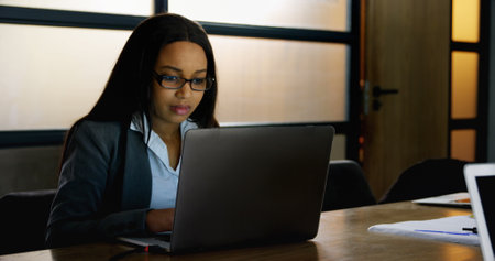 Front view of a happy smiling businesswoman using laptop for work in office. The attractive young...