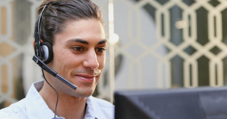 Smiling customer service executive talking on headset at deskの写真素材