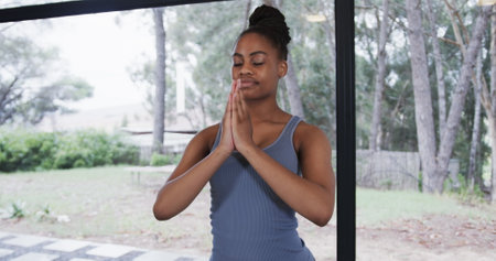 Portrait of african american woman meditating in yoga studio. Wellbeing, fitness, exercise and healthy lifestyle, unaltered.の写真素材