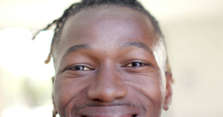 Portrait close up of happy african american man short dreadlocks smiling. Happiness, domestic life and lifestyle, unaltered.の写真素材