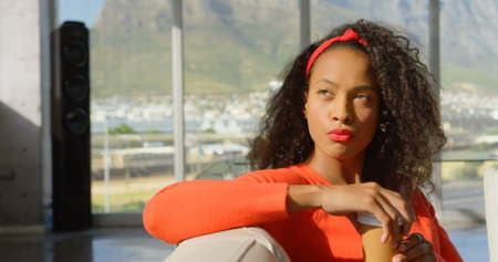 Front view of thoughtful young African American female executive sitting on the sofa in office. She is looking away 4kの写真素材