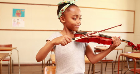 Cute pupil playing violin in classroom at the elementary schoolの写真素材