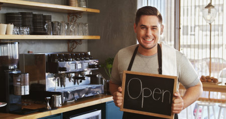 Portrait of Happy owner with chalkboard at counter in cafe