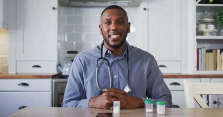 Portrait of african american doctor talking while having a image call at home. distant communication and telemedicine consultation concept.の写真素材