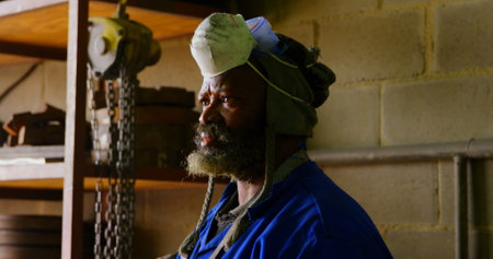 Thoughtful worker standing in foundry workshop. Worker looking away 4kの写真素材