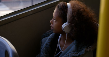 Thoughtful girl listening music while travelling in busの写真素材