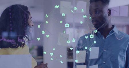 Image of network of medical icons over diverse male and female colleague brainstorming at office....