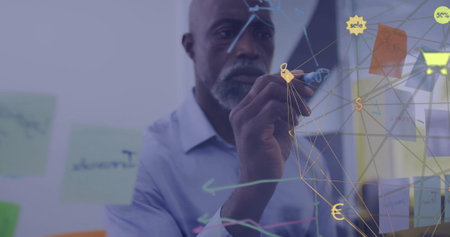 Image of network of retail icons over african american casual businessman brainstorming at work. Connection, business, network and communication, digitally generated image.の写真素材