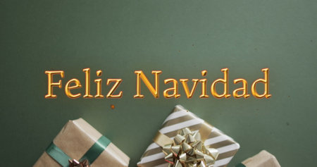 Feliz navidad text in orange over christmas gifts on green background. Christmas, tradition, greetings and celebration digitally generated image.の写真素材